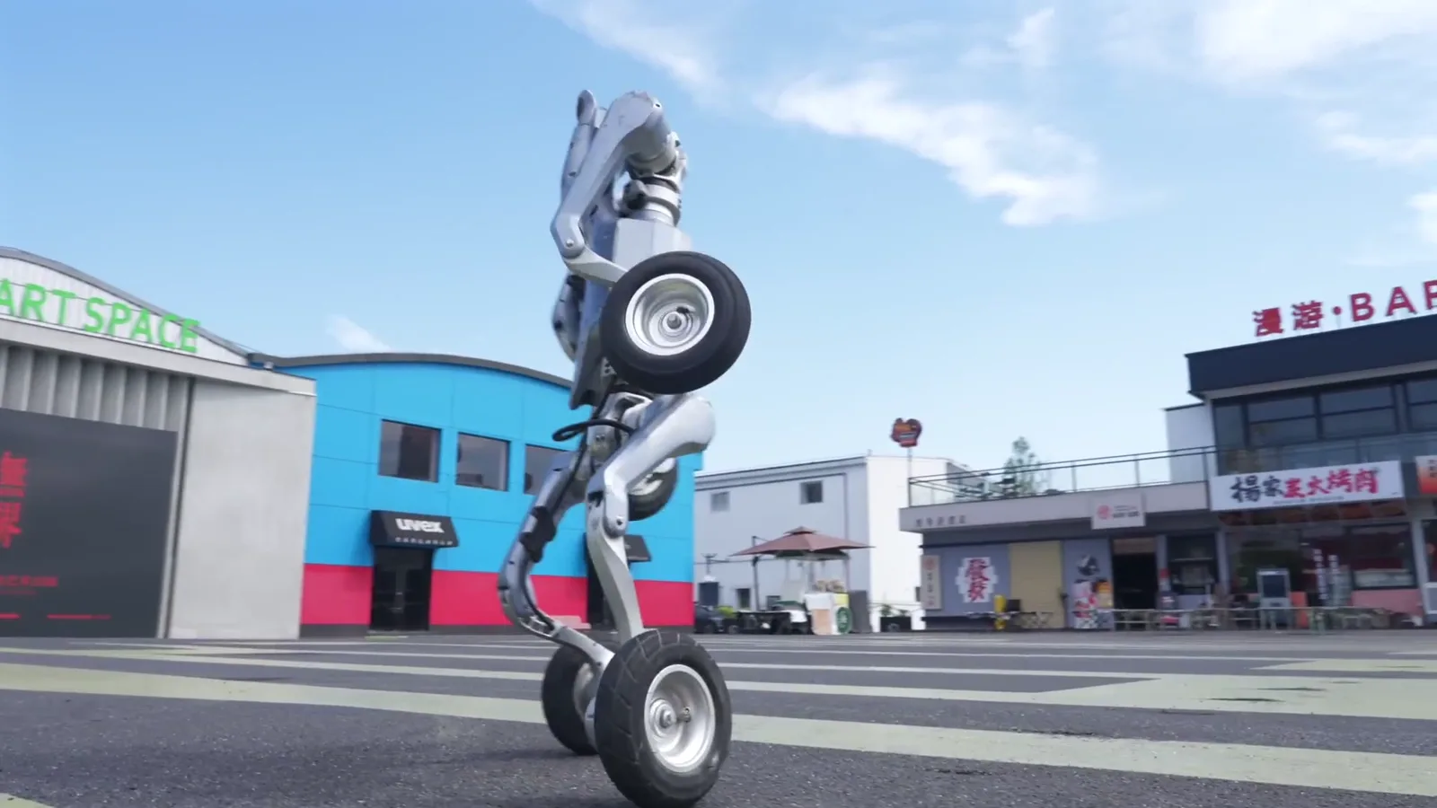 Unitree AS2-W dressé en équilibre sur deux roues devant des bâtiments colorés, figure spectaculaire en ville