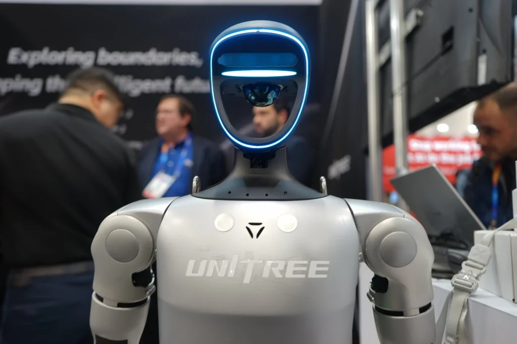 Robot humanoïde Unitree G1 entouré de visiteurs sur un stand de salon professionnel