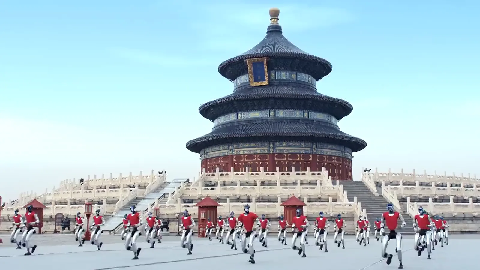 Des dizaines de robots humanoïdes Unitree G1 en tenue rouge courant en formation devant le Temple du Ciel à Pékin, extrait d’une vidéo officielle Unitree