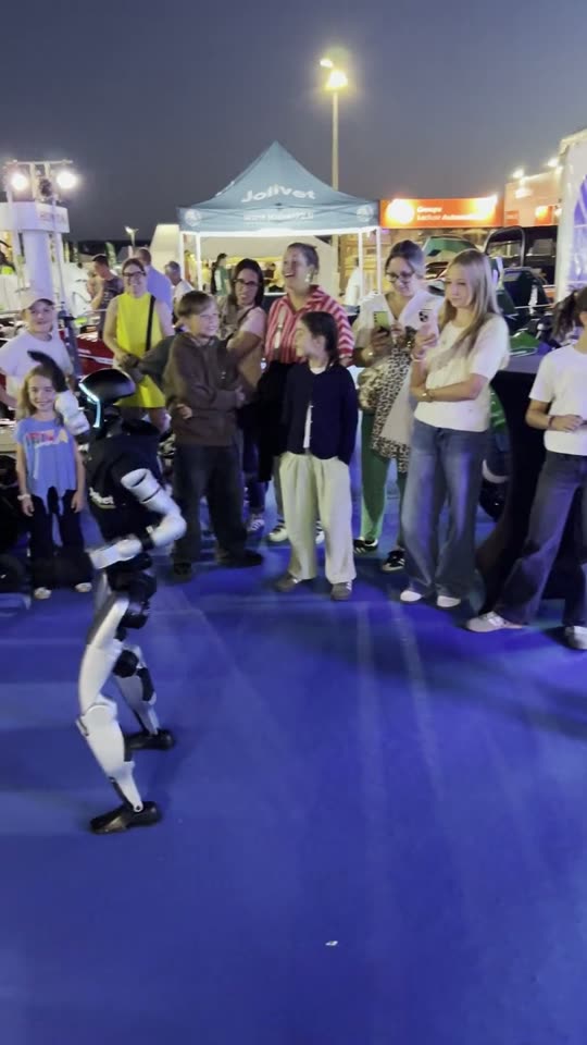 Le robot sur le tapis bleu, des familles à distance sous l'éclairage du stand