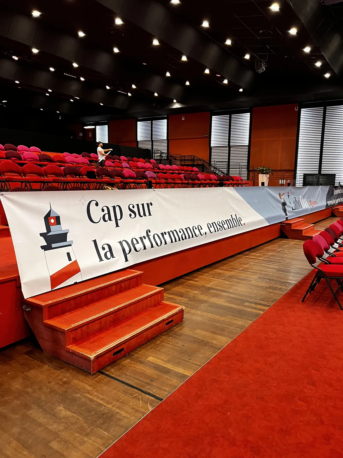 La banderole « Cap sur la performance, ensemble » posée au bord de la scène, devant les gradins rouges