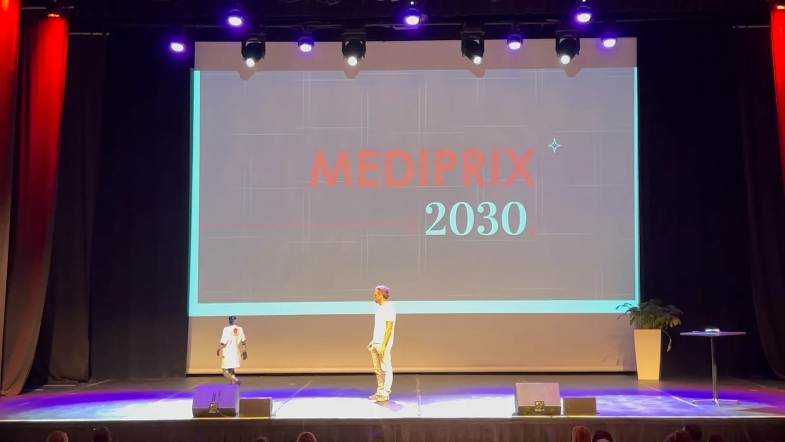 Sur la scène du Pasino, devant l'écran « Médiprix 2030 », le robot en blouse de pharmacien donne la réplique au pharmacien titulaire, filmé depuis la salle